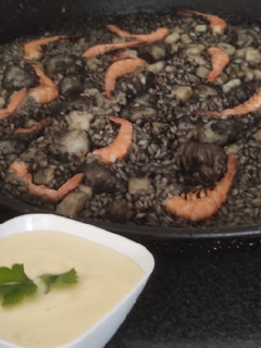 Una foto de Arroz negro con gambas, sepia y alioli