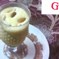 A picture of Mango shake with ice cream and dry fruits.