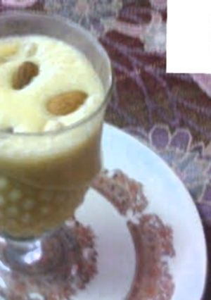 A picture of Mango shake with ice cream and dry fruits.