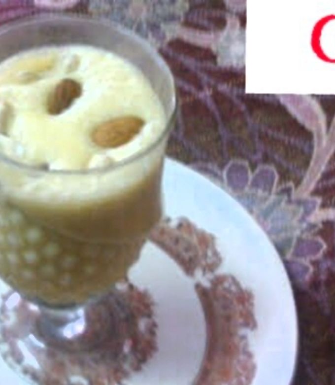 A picture of Mango shake with ice cream and dry fruits.