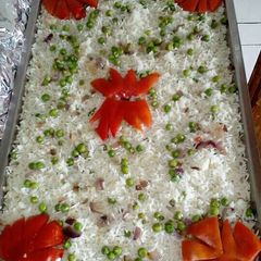 A picture of White rice with peas decorated with tomatoes.