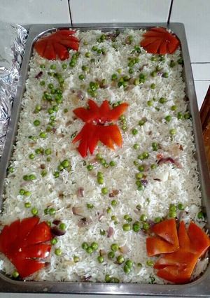 A picture of White rice with peas decorated with tomatoes.