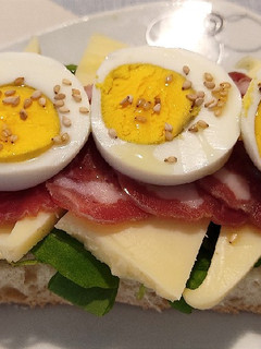 Una foto de Tosta de rúcula, queso, jamón y huevo