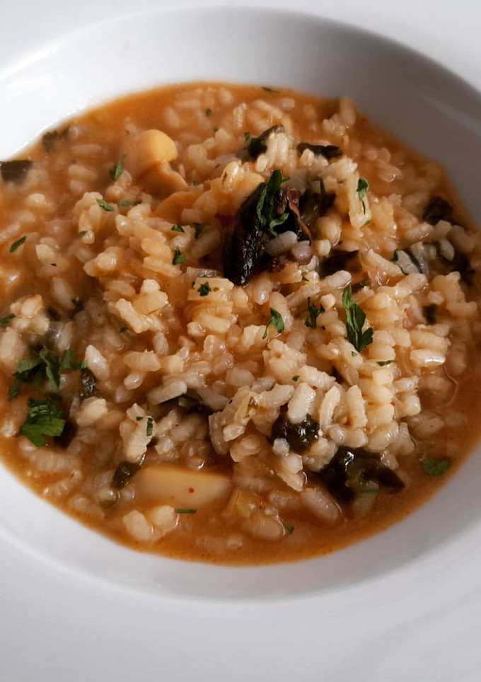 Una foto de Arroz caldoso de sepia, rape, setas y espinacas
