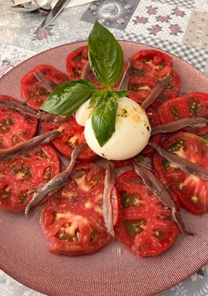 Una foto de Carpaccio de tomate con burrata y anchoas