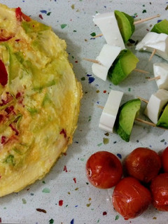 Una foto de Tortilla de verduras, tomatitos asados y pinchitos de aguacate con queso