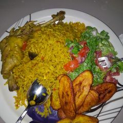 A picture of Jellof rice chicken with salad and plantain.