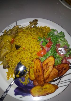 A picture of Jellof rice chicken with salad and plantain.