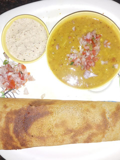 A picture of Masala Dosa with Sambar and Coconut Chutney.