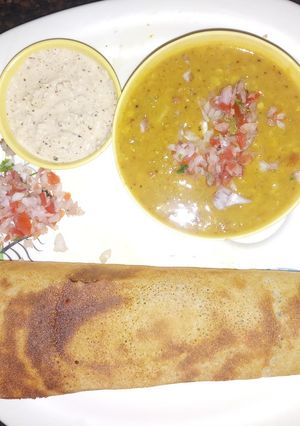 A picture of Masala Dosa with Sambar and Coconut Chutney.