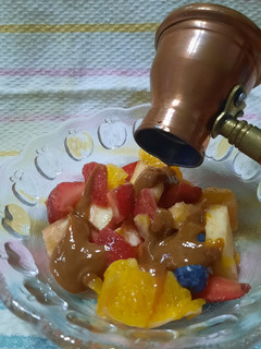 Una foto de Ensalada de frutas con salsa de dulce de leche y algo más.