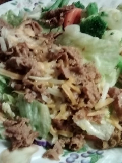 A picture of Cheese steak on lettuce bed.