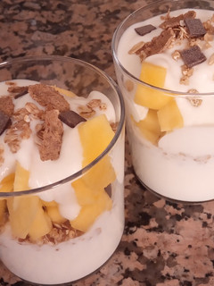 Una foto de Yogurt con mango y muesli, quinoa, chía, y chocolate negro