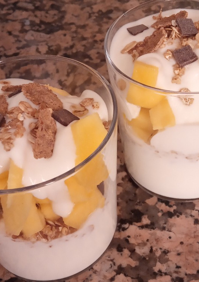 Una foto de Yogurt con mango y muesli, quinoa, chía, y chocolate negro