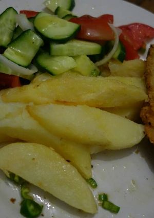 A picture of Fish and chips with cucumber salad.
