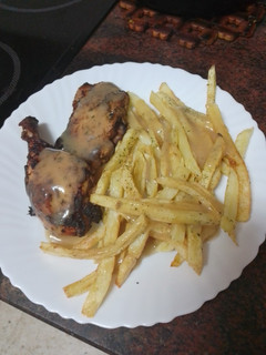 Una foto de Muslos de pollo adobados y asados en freidora de aire con papas fritas al ajillo y salsa del adobo