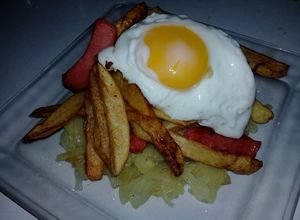 Una foto de Salchipapas con huevo al caballo y colchón de cebolla