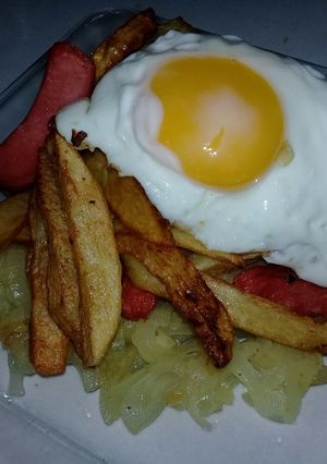 Una foto de Salchipapas con huevo al caballo y colchón de cebolla