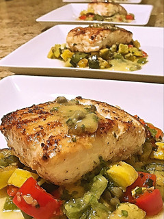 A picture of Wild halibut with lemon honey butter caper sauce and succotash.