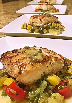 A picture of Wild halibut with lemon honey butter caper sauce and succotash.