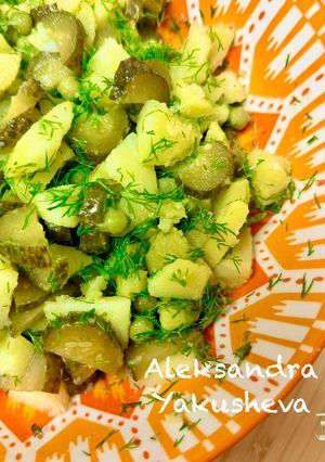 A picture of Potato salad with pickled cucumbers and green peas.