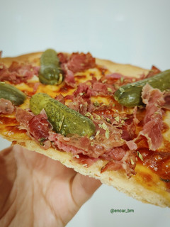 Una foto de Pizza blanca de pastrami y pepinillos
