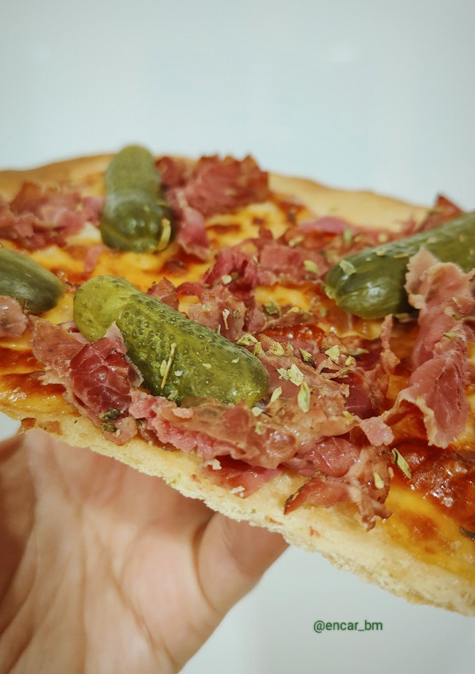 Una foto de Pizza blanca de pastrami y pepinillos