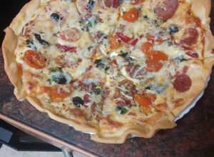 Una foto de Pizza de jamón serrano, fuet, espinacas y tomate cherry