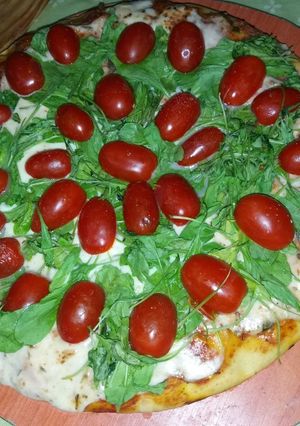 Una foto de Pizza de rúcula y tomates cherry