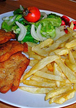 Una foto de Filetes de pechuga de pollo rebozadas con patatas pajas y ensalada