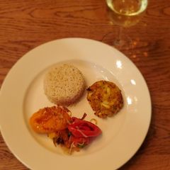 A picture of Crab cakes with rice and sautéed veggies.