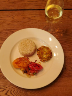 A picture of Crab cakes with rice and sautéed veggies.