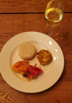 A picture of Crab cakes with rice and sautéed veggies.