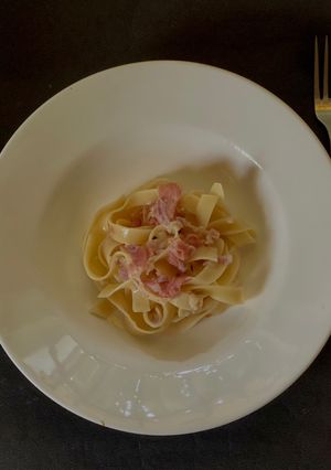 A picture of Tagliatelle with white sauce, ham.