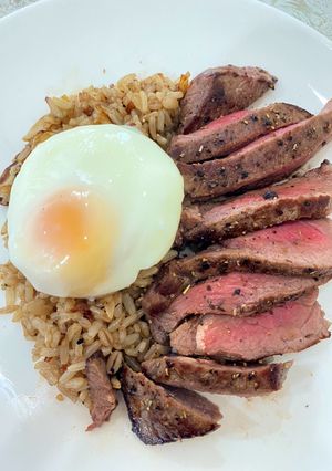 A picture of Garlic fried rice with sliced grilled beef sirloin.