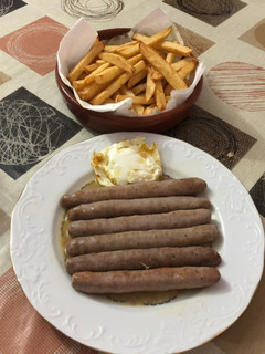 Una foto de Salchichas cocidas con vino patatas fritas y huevo frito