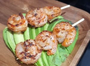 Una foto de Brocheta de camarones sobre palta