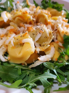 Una foto de Tortellini con rúcula y aceite de albahaca