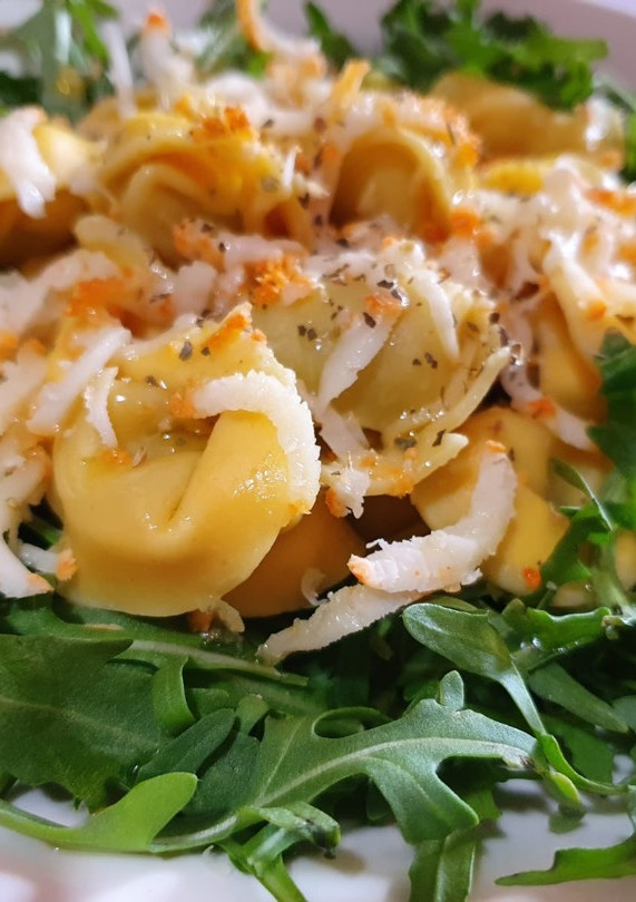 Una foto de Tortellini con rúcula y aceite de albahaca