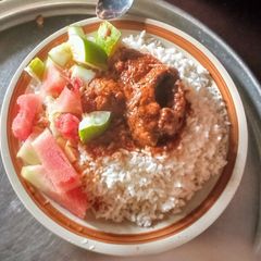 A picture of Rice and tomato sauce with fruit salad.
