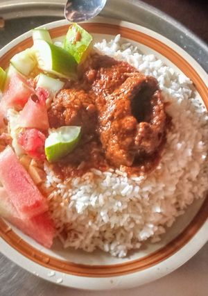 A picture of Rice and tomato sauce with fruit salad.