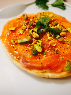 Una foto de Tosta sobre pan de pita de salmón, crema de huevo y queso gorgonzola con cobertura de pistachos