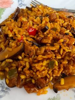 Una foto de Chicharrones de secreto ibérico con setas y arroz en paella