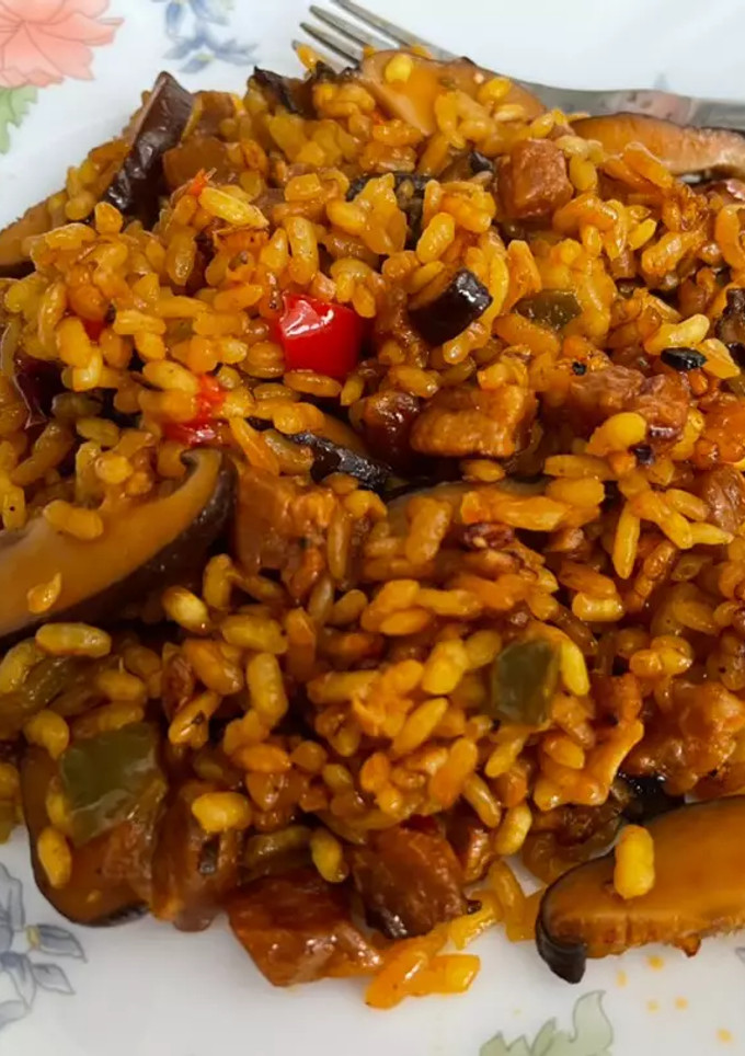 Una foto de Chicharrones de secreto ibérico con setas y arroz en paella