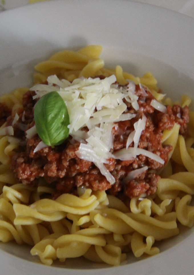 Una foto de Fusilli a la bologñesa con virutas de parmesano 