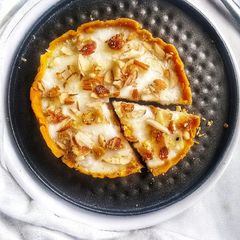 A picture of Besan laddoo tart filled with rice pudding topped with nuts.