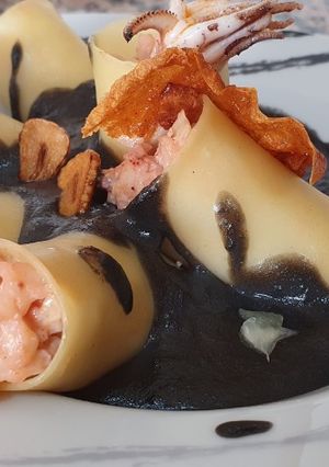 Una foto de Macarrones rellenos de chipirones y gambas con salsa de tinta