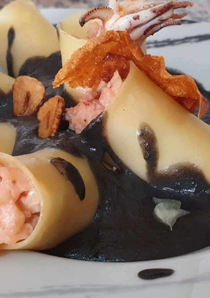 Una foto de Macarrones rellenos de chipirones y gambas con salsa de tinta