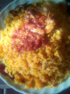 A picture of Palm oil rice and sauced fish.