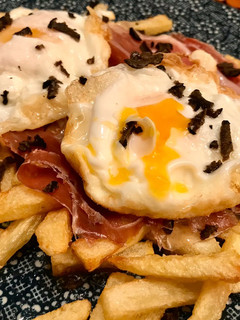 Una foto de Huevos rotos con trufa negra y jamón ibérico